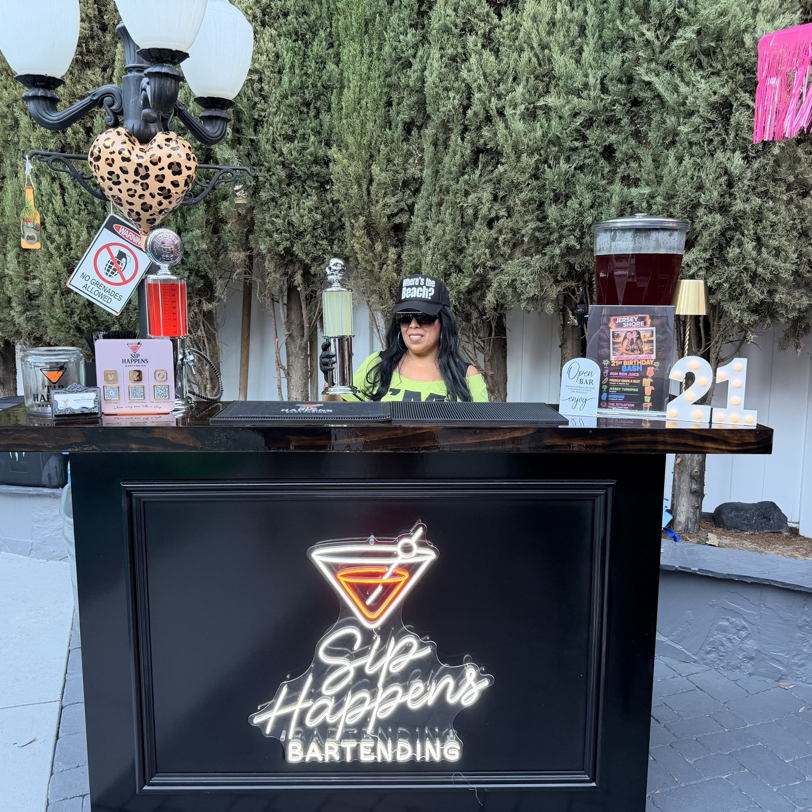 Sip Happens Bartending neon bar set up outdoors for a 21st birthday party with drink dispensers and a marquee 21 sign